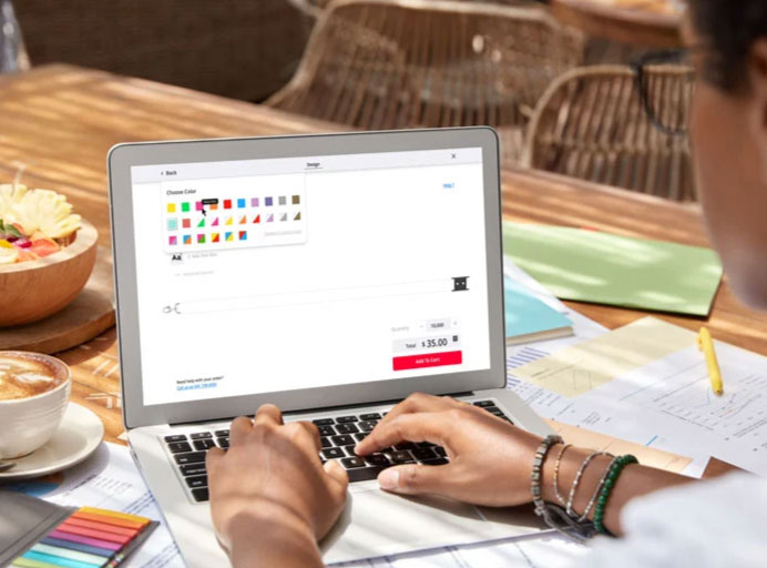 Interface de Personnalisation en Ligne – IDCGO Personne utilisant un ordinateur portable pour personnaliser un produit en ligne via une interface de configuration.